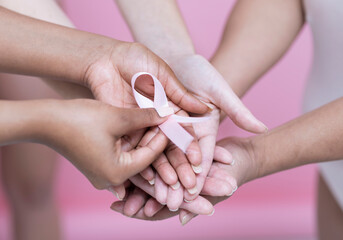 Close-up of women's hands holding pink breast cancer awareness ribbon