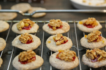 Christmas bakery in the kitchen: Delicious homemade cookies for advent or christmas - freshly baked and garnished with walnuts, jam, candied orange peel, made with love, blurred background, close up
