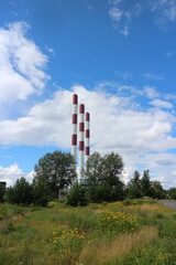 striped chimneys of thermal power plant rural landscape flowering meadow in the foreground