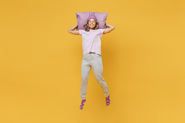 Full body young calm woman wear purple pyjamas jam sleep eye mask rest relax at home jump high hold...