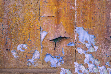 cracked grunge paint detail with orange color and pale blue underneath the cracked paint