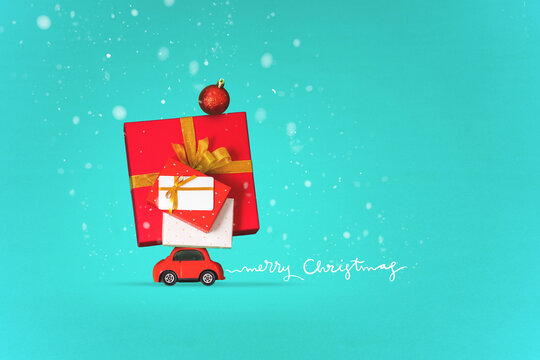 Christmas background, red small car transports many gifts on roof under snowfall