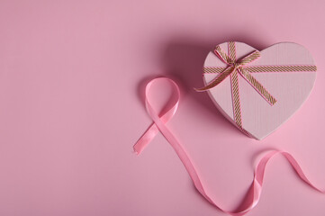 Flat lay. Still life with pink satin ribbon and pink pastel heart shaped gift box on color background. Breast Cancer Awareness Campaign. October 1. Assistance, help, support. Health care and medicine