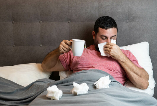 Hombre de mediana edad en cama enfermo con síntomas de gripe
