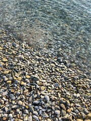 sea pebble coastline, transparent sea water, pebbles bottom