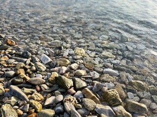sea pebble coastline, transparent sea water, pebbles bottom