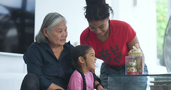Girls with grandmother playing with Maneki-neko and Buddha figurines at home