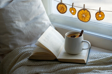 A hot, fragrant cup of tea with spiced orange slices on the windowsill on a winter morning.