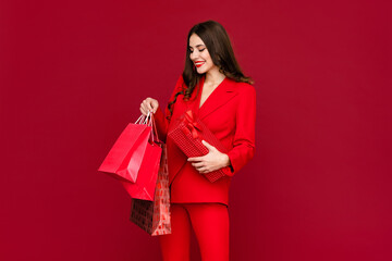 Fototapeta na wymiar attractive woman in red with shopping bags sale on red background