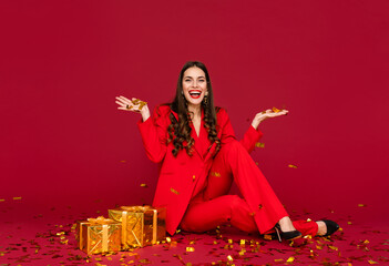 attractive woman celebrating Christmas on red background in confetti