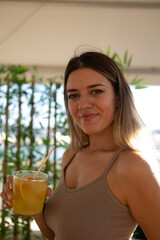 Young woman holding her cocktail and smiling. Bamboo background. 