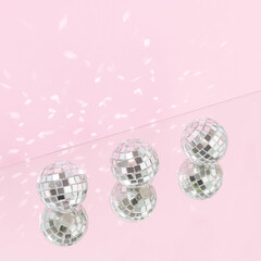 Three shiny disco balls with mirror reflection against bright pink background. Minimal holidays celebration party creative concept. Retro 80s or 90s disco aesthetic.
