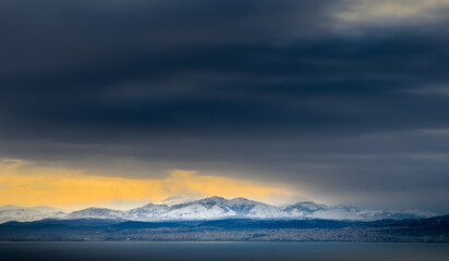 Sea and snowcapped mountain against clouds
