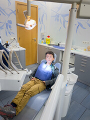 Cute boy sitting on dentist's chair in clinic
