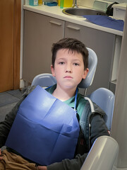 Serious boy sitting on dentist's chair in hospital