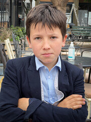 Boy in suit sitting at sidewalk restaurant