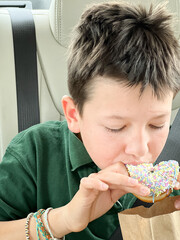 Boy eating doughnut in car