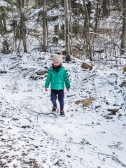 Boy standing on snow covered land in forest