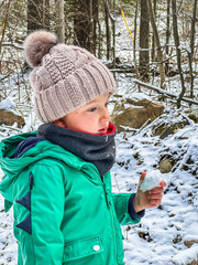 Thoughtful boy holding snow in forest
