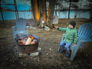 Boy roasting marshmallow over campfire in forest