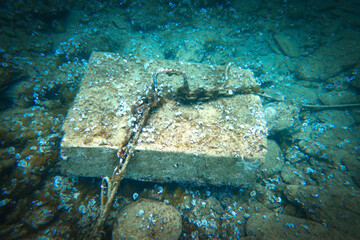 Chains tied to hook on block in sea