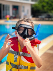Boy wearing snorkel and life jacket at poolside