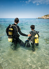 Son and father with aqualungs in ocean