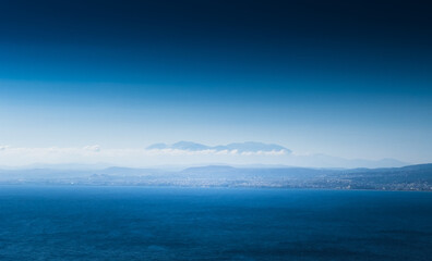 View of seascape and mountain against blue sky