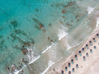Drone shot of deck chairs and parasols at beach