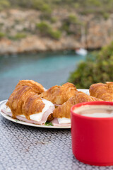Breakfast of Coffee and croissant with ham and cheese in the outdoors