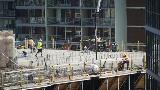 Workers at top of building pouring concrete at construction site