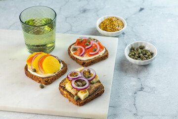 Three Scandinavian open sandwiches with herrings, salmon and potatoes on marble background. Copy...