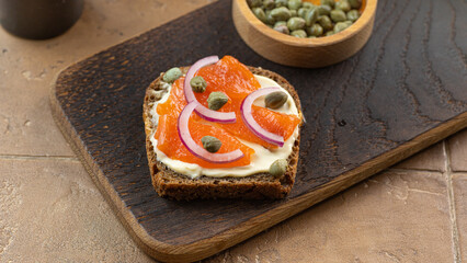 Smorrebrod - traditional Danish sandwiches. Black rye bread with salmon, cream cheese, capers. Side view, close up