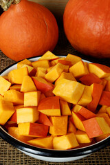Chopped red kuri squash chunks in enamel bowl. Organic cooking ingredient.