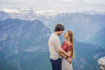 Naklejka premium Man and woman happy couple tourists on background of Breathtaking panoramic view of the Grlo Sokolovo gorge in Montenegro. In the foreground is a mountain, the flat side of which forms a cliff, and