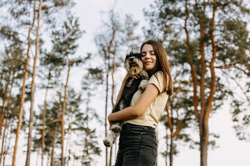 Young brunette woman hugging a miniature schnauzer breed dog, smiling.