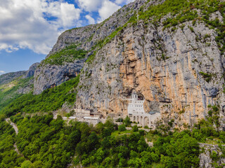 Fototapeta na wymiar Monastery of Ostrog, Serbian Orthodox Church situated against a vertical background, high up in the large rock of Ostroska Greda, Montenegro. Dedicated to Saint Basil of Ostrog