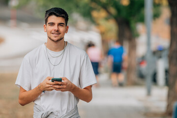 portrait of young man smiling in the street with mobile phone or smartphone