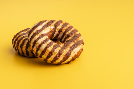 Donut with chocolate and caramel icing on yellow background.