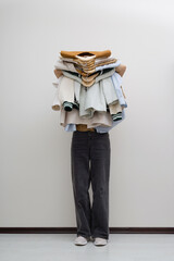 Woman holding pile of clothes. Minimal fashion faceless portrait.