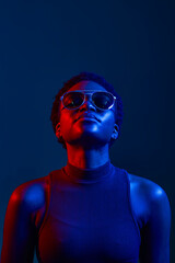 Woman in sunglasses looking up studio shot over dark