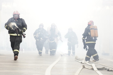 Rescuers firefighters go in the smoke, carry equipment.