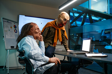 Two zombie businessmen looking at laptop screen