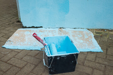 Roller with blue paint. DIY concept. incorrect wall painting