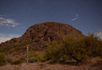 A meteor streaking above a desert butte on a starry night