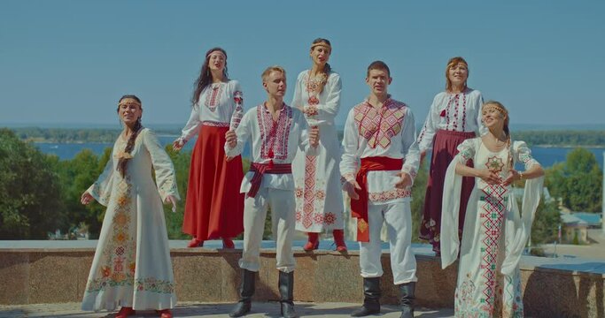 Ukrainians stand in the park and sing songs, beautiful folk costumes with embroidery. Ukrainian men and women enjoy life, they smile. Friendly people. 4k, ProRes