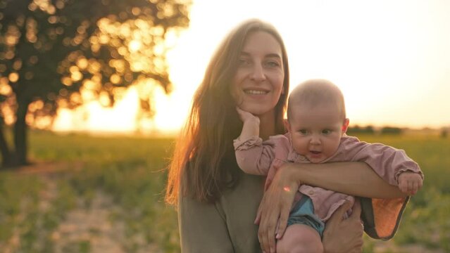 Beautiful mother kisses her little daughter and smiling. Portrait of a happy child. Family in the sun at sunset. Education, care.