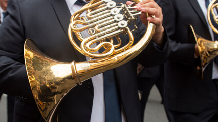 Detail of the hands of a musician parading in the street playing the horn