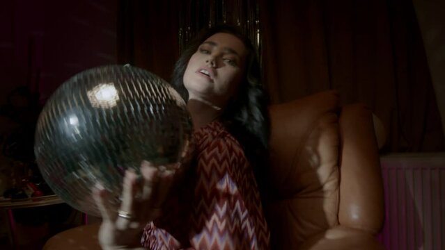 A woman holding a disco ball and dancing 