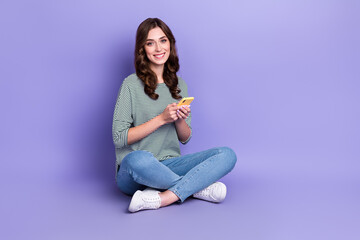 Photo of pretty cute lady addicted user sit floor rejoice new quality gadget empty space isolated on purple color background